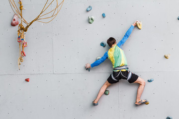 Young Man Climbs Up An Artificial Rock Wall, sport and fitness concept