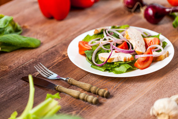 Fresh salad with chicken, tomato and greens on wooden background top view. Healthy food.