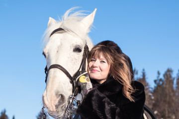 Obraz premium Nice girl and white horse in a forest in a winter