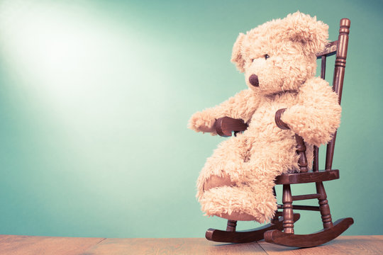 Teddy Bear toy on wooden chair in front mint green background. Retro old style filtered photo