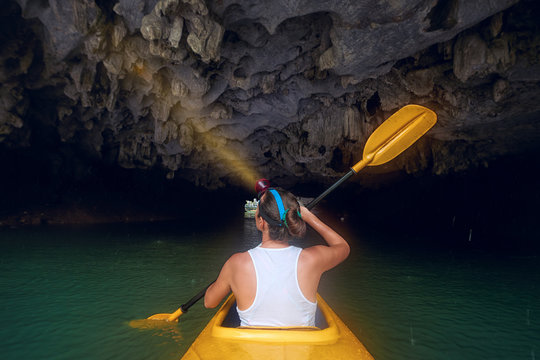 Woman explore and paddling the kayak inside karst cave