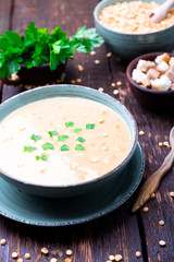 Pea soup in green bowl on brown wooden background.  Dry yellow pea. Vegan food.