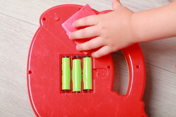 hand the child put the batteries in the red toy