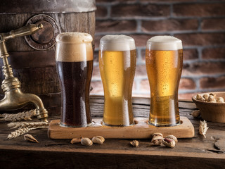 Glasses of beer and ale barrel on the wooden table. Craft brewery.