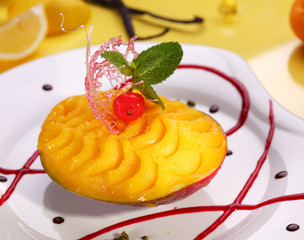 Mango dessert decorated with mint leaf and caramel decoration.