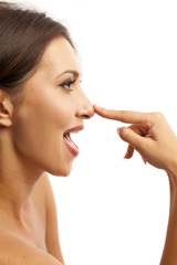 Beautiful smiling young woman touching her nose on white background