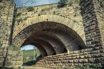 Fototapeta na wymiar View of the arcs of the old historic stone bridge