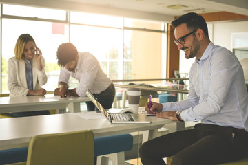 Obraz premium Business man working in office on laptop and writing document. Business people working in office.