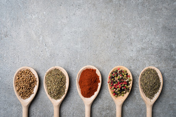 Fresh herbs and spices on wooden spoons.