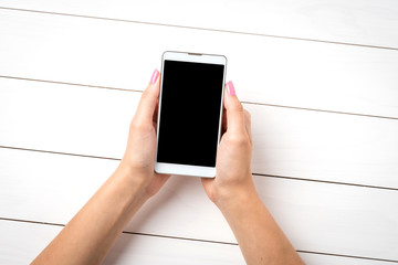 Woman holding smart phone over white wooden table. Close up