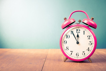 Old alarm clock with five minutes to twelve o'clock. Retro style filtered photo