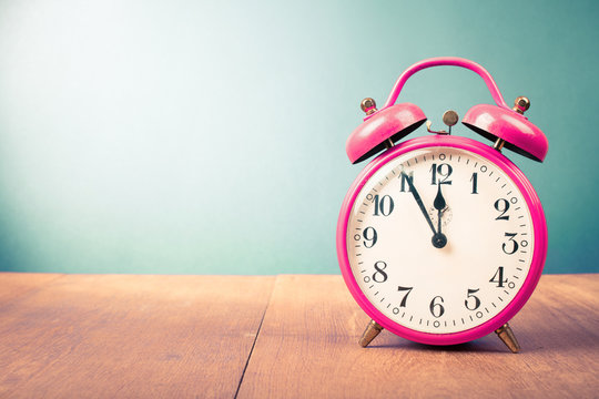 Old alarm clock with five minutes to twelve o'clock. Retro style filtered photo