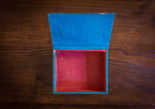 Scatola azzurra e rossa, aperta e vuota su tavolo di legno scuro