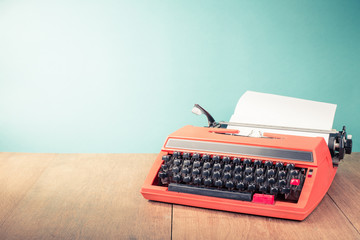 Retro old typewriter with paper sheet on wooden table front mint green background. Vintage style...