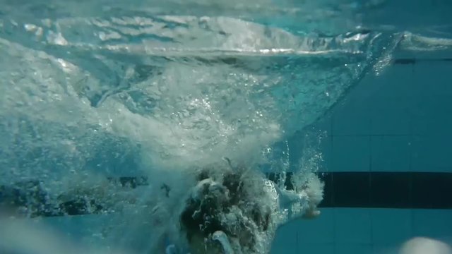 Young boy jumping from spring board into swimming pool and dives - vacations resort