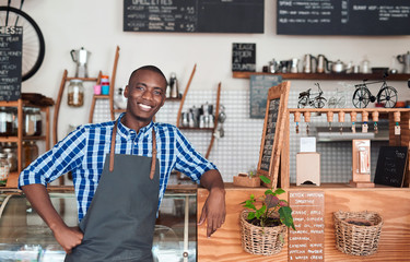 Smiling barista leaning on the counter in a cafe