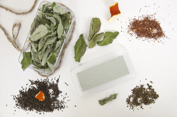Mock up of box with mint and melissa, green and black tea, dried orange peel on white background. Top view.