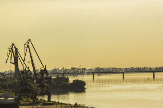 Port cranes against the background of the sunset sun in the evening