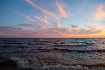 North seascape on Lake Onega - waves beat against the granite shore which reflects the rays of the setting sun.