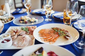 Sliced meat and fish served on white plates on blue dishes
