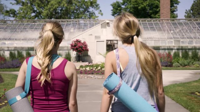 Young Women Walk Through Botanical Garden On Their Way To Yoga Class 