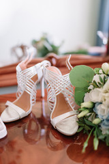 Bride's shoes, box with wedding rings, boutonniere and bouquet stand on the table
