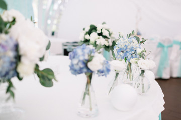 Blue flowers in glass vases stand on the table