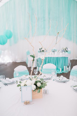 Dinner table decorated with white flowers and mint cloth