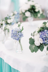 Blue flowers in glass vases stand on the table