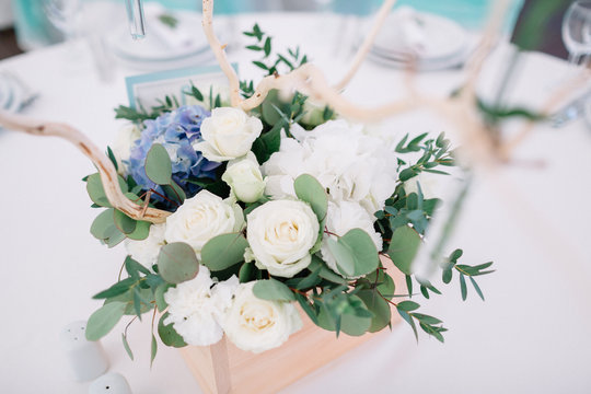 Delicate white roses in a wooden box stand on the table