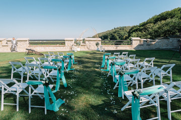 Chairs for guests stand on the lawn before a wedding altar