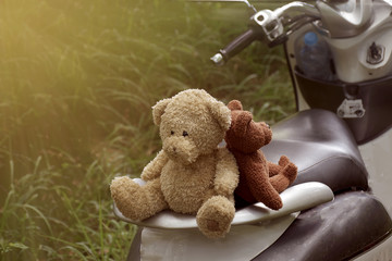 Two teddy bear sitting on motorcycle with sun light