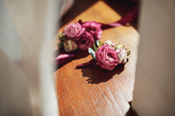 Delicate boutonniere made of roses lies on the windowsill