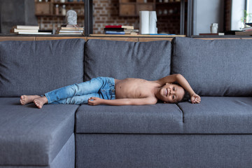 shirtless little kid playing on sofa