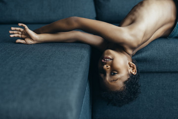 shirtless little kid playing on sofa
