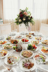 Tall vases with red and white flowers stand on the dinner tables