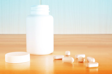 Pharmacy theme. White bottle of pills on a wooden surface. Closeup.