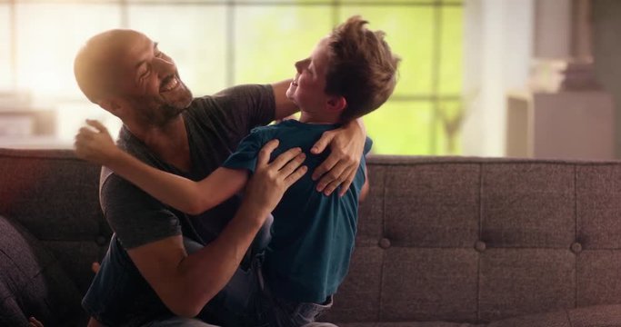 Father and son fooling around and hugging afterwards on the couch