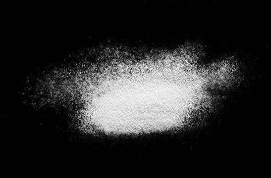 Pile of wheat flour isolated on black background, top view
