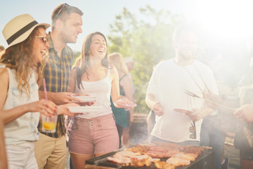 Small group of friends drinking alcohol and having a meal at barbecue party