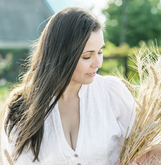 Beautiful sexy female with long hair holding wheat ears in wheat field at sunny sunner day