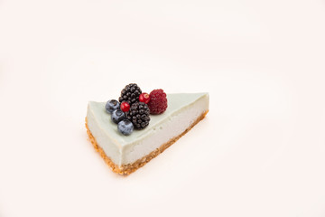 Side view of blue cheesecake with different berries
