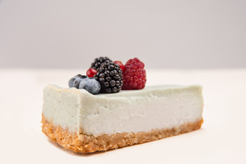Side view of blue cheesecake with different berries