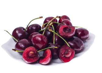 Whole and halves of ripe cherries on white plate
