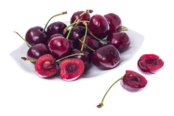 Whole and halves of ripe cherries on white plate