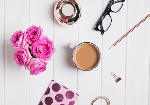 Coffee, roses and other feminine accessories on the white wooden background