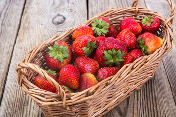 Strawberries in wicker basket on wooden background