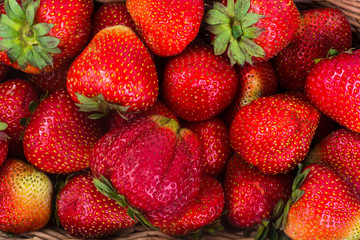Strawberries in wicker basket on wooden background