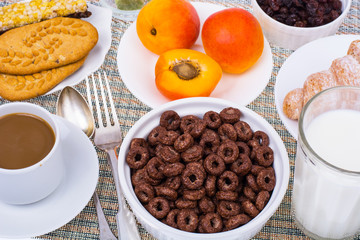 Breakfast table with croissant, muesli, milk, honey and fruits