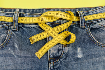 Blue jeans with yellow measure tape: dieting concept